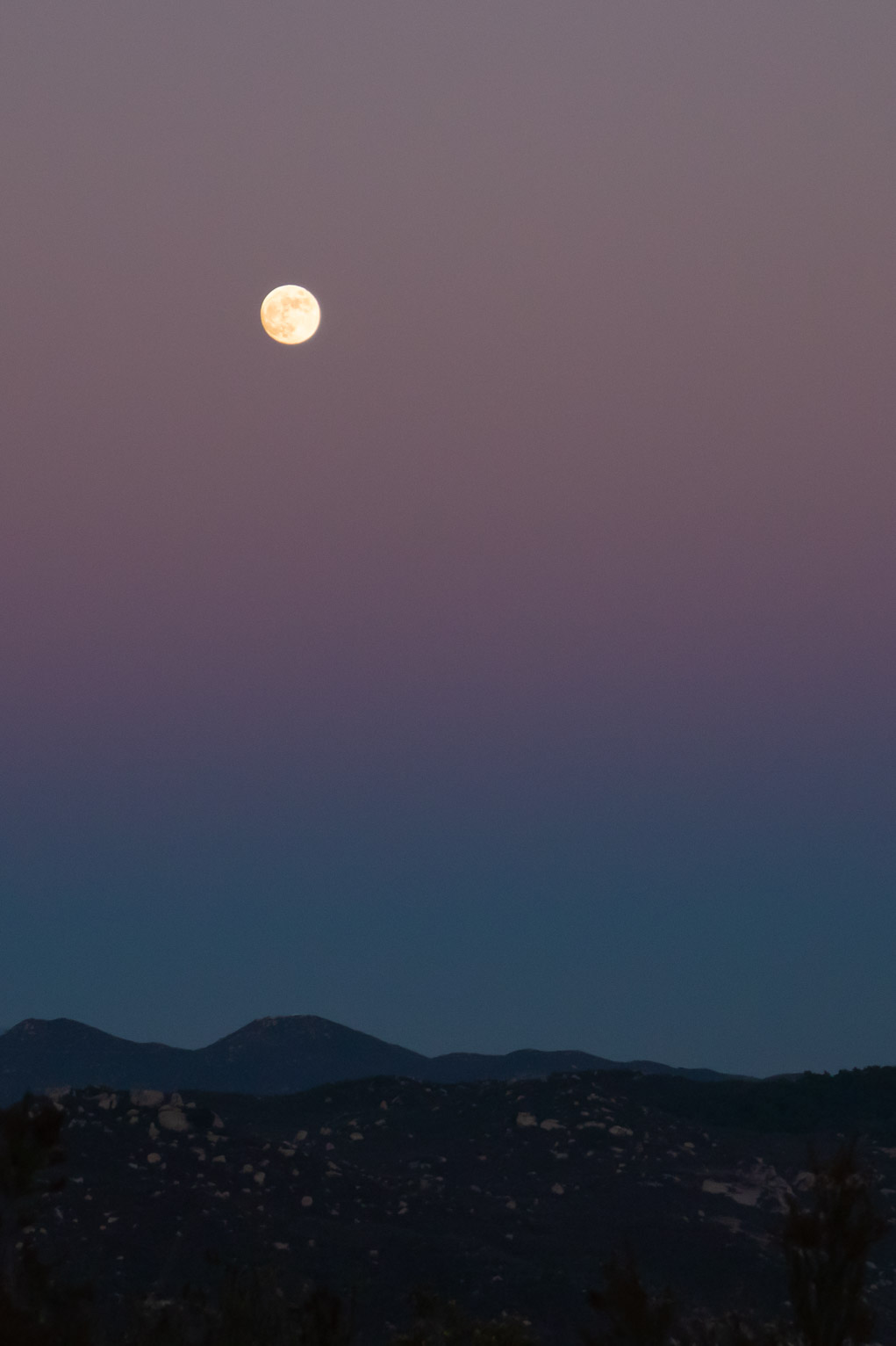 full moon in sunset sky over mountains